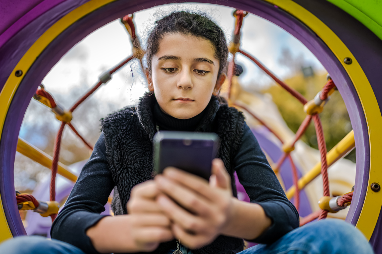 Little girl playing on mobile phone instead of enjoying the Park